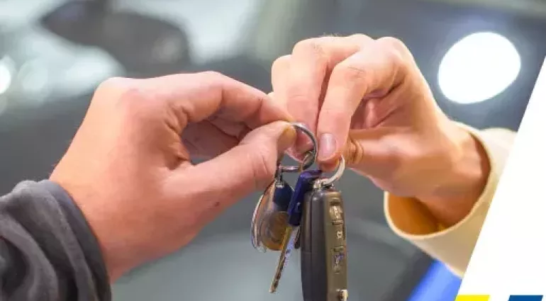 Un tecnico consegna le chiavi dell'auto a un cliente dopo aver completato una riparazione del vetro sull'auto.